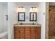 Bathroom featuring double sinks with granite counters, wood cabinets, and tiled walls at 5125 Ariton Rd, North Port, FL 34288