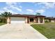 Charming single-story home with a manicured lawn and a spacious two car garage on a sunny day at 5125 Ariton Rd, North Port, FL 34288