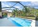 Inviting screened-in pool area with clear blue water, surrounded by a patio and lush landscaping at 5125 Ariton Rd, North Port, FL 34288