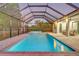 A twilight view of a private in-ground pool and spa under a screened enclosure at 7344 Manthey Ave, North Port, FL 34291