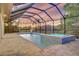 Screened pool area featuring a pool and hot tub with brick pavers, an outdoor grill, and a sunset sky at 7344 Manthey Ave, North Port, FL 34291