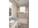 Well-lit bathroom featuring a shower over bath, tiled walls and floor and a vanity with marble counter-top at 1182 Yorkshire St, Port Charlotte, FL 33952