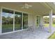 A covered patio with ceiling fan, brick pavers, and outdoor seating with a view of the lush green lawn at 1182 Yorkshire St, Port Charlotte, FL 33952