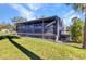 Side view of house featuring a screened porch with latticework and well-maintained green lawn at 14760 Conway Rd, Port Charlotte, FL 33981