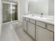 Modern bathroom featuring a double sink vanity, tiled floor, and glass shower enclosure at 15172 Mcgraw Ave, Port Charlotte, FL 33953
