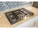 Close-up of a gas cooktop with granite countertops and stylish tile backsplash at 15931 Sugar Hill Dr, Punta Gorda, FL 33982