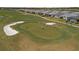 People golf on a manicured green surrounded by sand traps in this bird's eye view at 15931 Sugar Hill Dr, Punta Gorda, FL 33982