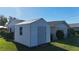White storage shed sits on a well-maintained lawn beside a house with a screened in patio at 18427 Goodman Cir, Port Charlotte, FL 33948