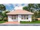 White brick home featuring large windows and a terra cotta colored roof with manicured landscaping at 20208 Winkler Ave, Port Charlotte, FL 33954