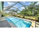 Relaxing screened-in pool with a clear blue water, a brick paver deck, and lush greenery, creating a serene backyard retreat at 2132 Nuremberg Blvd, Punta Gorda, FL 33983