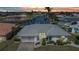 Waterfront home featuring a gray tile roof, screened garage, a concrete driveway, and mature landscaping at sunset at 2350 W Marion Ave, Punta Gorda, FL 33950