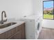 Bright laundry room features modern white appliances, sink with stylish fixtures, and a window offering a pleasant view at 24259 Peppercorn Rd, Punta Gorda, FL 33955