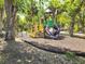 Community playground featuring a swing set, slide, and climb structure amongst mature trees at 24259 Peppercorn Rd, Punta Gorda, FL 33955