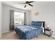 Bright bedroom featuring a window with curtains, a ceiling fan, and a navy blue bedspread at 25336 Deep Creek Blvd, Punta Gorda, FL 33983