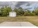 Large storage shed in a spacious backyard with green grass, bordered by mature trees and landscaping at 2592 Coolidge Ave, North Port, FL 34286