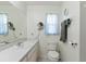 Bright bathroom featuring a white vanity with a sink, a mirror, and toilet at 2631 Tomaso Rd, North Port, FL 34287