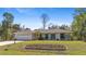 Inviting single-story home featuring a manicured lawn and a colorful flower bed, adding charm to the property at 2631 Tomaso Rd, North Port, FL 34287