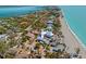 Stunning aerial view of coastal home near pristine beach with turquoise waters and lush palms at 6112 Gnarled Oak Dr, Englewood, FL 34223