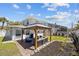 Spacious backyard featuring a charming gazebo, lush lawn, screened pool area and outdoor seating at 6112 Gnarled Oak Dr, Englewood, FL 34223