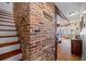 Foyer featuring a brick accent wall and a view of the living room, complemented by wood flooring at 6112 Gnarled Oak Dr, Englewood, FL 34223