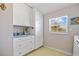 Bright laundry room with white cabinets and a view from the window at 6112 Gnarled Oak Dr, Englewood, FL 34223