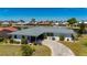 Waterfront home featuring mature landscaping, tile roof, and circular driveway surrounded by lush tropical foliage at 1206 Winward Ct, Punta Gorda, FL 33950