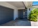 Front door and garage featuring a wreath and American flag decor with tropical landscaping at 1206 Winward Ct, Punta Gorda, FL 33950