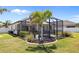 Backyard featuring a screened-in lanai with outdoor dining and landscaped garden beds at 15288 Mille Fiore Blvd, Port Charlotte, FL 33953