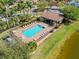 Aerial view of a community pool with lounge chairs, lush landscaping, and a cabana area at 15288 Mille Fiore Blvd, Port Charlotte, FL 33953