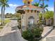 Exterior shot of the gated community entrance with terracotta tile roof, landscaping, and brick-paved road at 15288 Mille Fiore Blvd, Port Charlotte, FL 33953