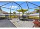 Outdoor dining in screened patio with table, chairs, BBQ grill, and view of fenced backyard at 15288 Mille Fiore Blvd, Port Charlotte, FL 33953