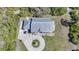 An aerial perspective of a home showcasing its pristine metal roof, circular driveway, and manicured lawn at 16180 Forest Glen Ct, Punta Gorda, FL 33982
