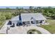 Aerial view of a sprawling home featuring a circular driveway, manicured lawn, and a metal roof at 16180 Forest Glen Ct, Punta Gorda, FL 33982