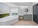 Bright bathroom with large tub under window, vanity with stool, and access to linen closet at 16180 Forest Glen Ct, Punta Gorda, FL 33982