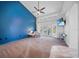 Bright main bedroom featuring a ceiling fan, large windows, and a blue accent wall at 16180 Forest Glen Ct, Punta Gorda, FL 33982