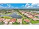 Stunning aerial view of the neighborhood with lake, manicured lawns, and tile roofs, under a partly cloudy sky at 24407 Riverfront Dr, Punta Gorda, FL 33980