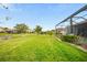 Expansive backyard with green lawn, serene water view, and screened-in patio at 24407 Riverfront Dr, Punta Gorda, FL 33980