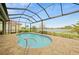 Screened-in pool area with a view of the lake in the distance, complemented by tiled flooring and ample lounging space at 24407 Riverfront Dr, Punta Gorda, FL 33980
