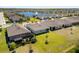 Overhead view of homes with screened patios, green lawns, and a community pond in the background at 25292 E Lenox Cir, Punta Gorda, FL 33950