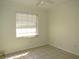 This bedroom has neutral walls, tiled flooring, a ceiling fan, and a bright window providing natural light at 409 Ricold Ter, Port Charlotte, FL 33954