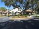 A large clubhouse with a flag pole is surrounded by mature trees, shrubbery, and parking spaces at 409 Ricold Ter, Port Charlotte, FL 33954