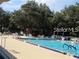 Outdoor swimming pool lined with chairs and tables with leafy trees behind the fence at 409 Ricold Ter, Port Charlotte, FL 33954