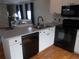 Modern kitchen featuring white cabinets, black appliances, and stylish backsplash, seamlessly connecting to living area at 5421 Holiday Park Blvd, North Port, FL 34287