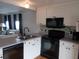 Modern kitchen featuring white cabinets, black appliances, and stylish backsplash, seamlessly connecting to living area at 5421 Holiday Park Blvd, North Port, FL 34287