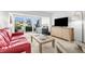 Contemporary living room with a large TV, comfortable sofa, and serene views of the lush outdoor landscape at 600 Sutton Pl # 101B, Longboat Key, FL 34228