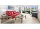Cozy living area with a plush red sofa, stylish coffee table, and sliding glass doors leading to outdoor space at 600 Sutton Pl # 101B, Longboat Key, FL 34228