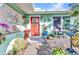 Inviting front entrance featuring a red door, decorative wreath, and charming outdoor decor and greenery at 82 Caddy Rd, Rotonda West, FL 33947