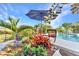 Backyard pool with umbrella and seating, surrounded by tropical landscaping at 82 Caddy Rd, Rotonda West, FL 33947