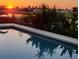 Beautiful pool reflecting a brilliant sunset and tropical plants at 82 Caddy Rd, Rotonda West, FL 33947