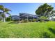 Backyard view of a screened lanai, lush lawn, and mature trees at 955 Don Juan Ct, Punta Gorda, FL 33950